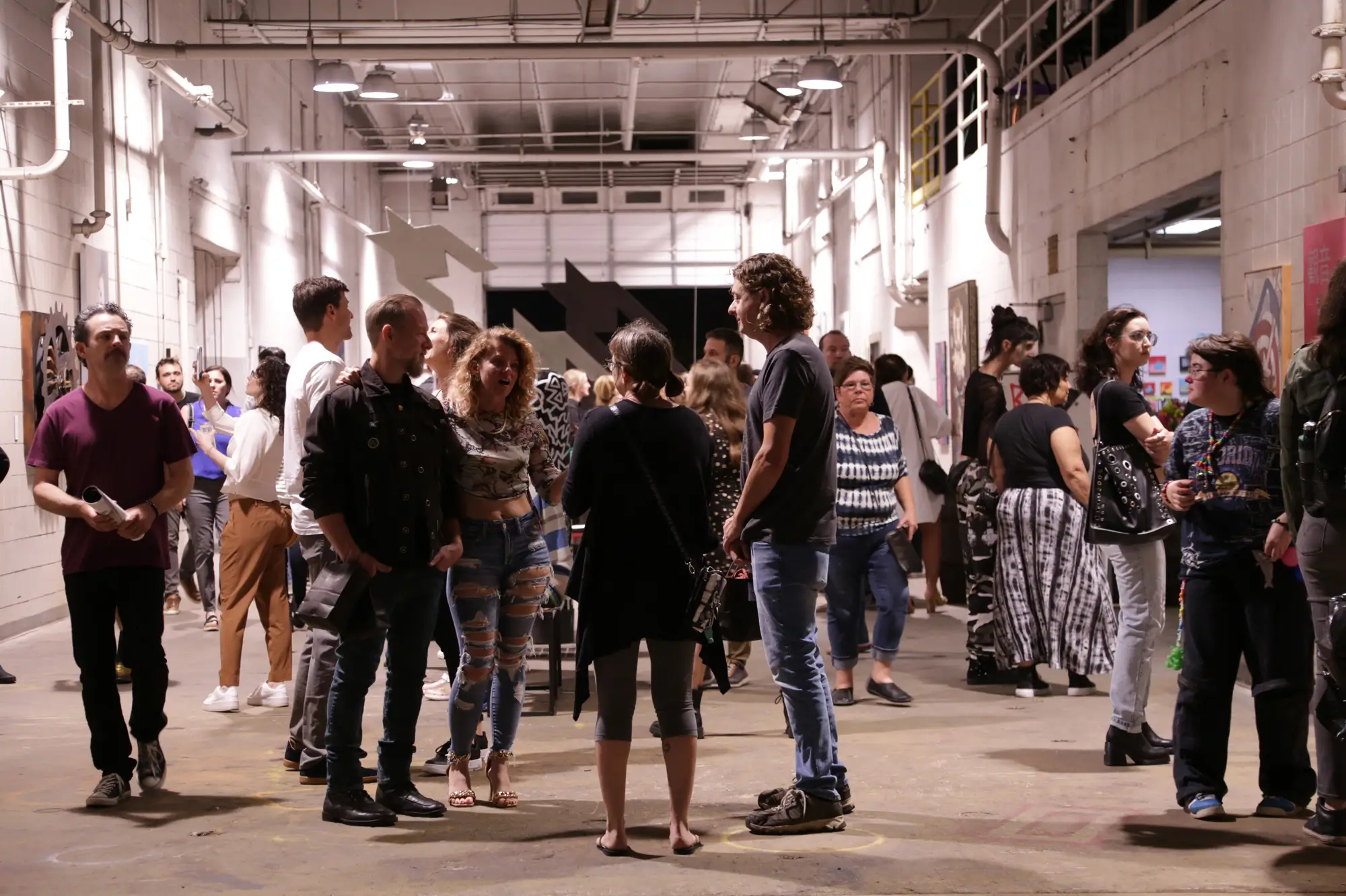 A crowd of people standing in a warehouse.