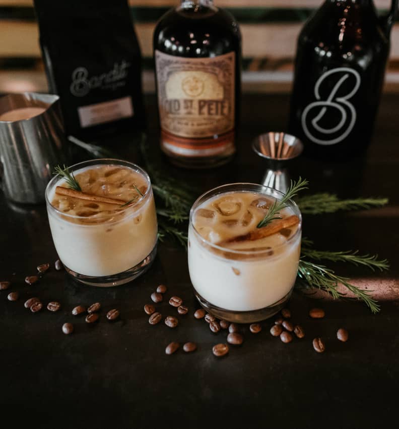 Two glasses of iced coffee with cinnamon sticks and coffee beans.